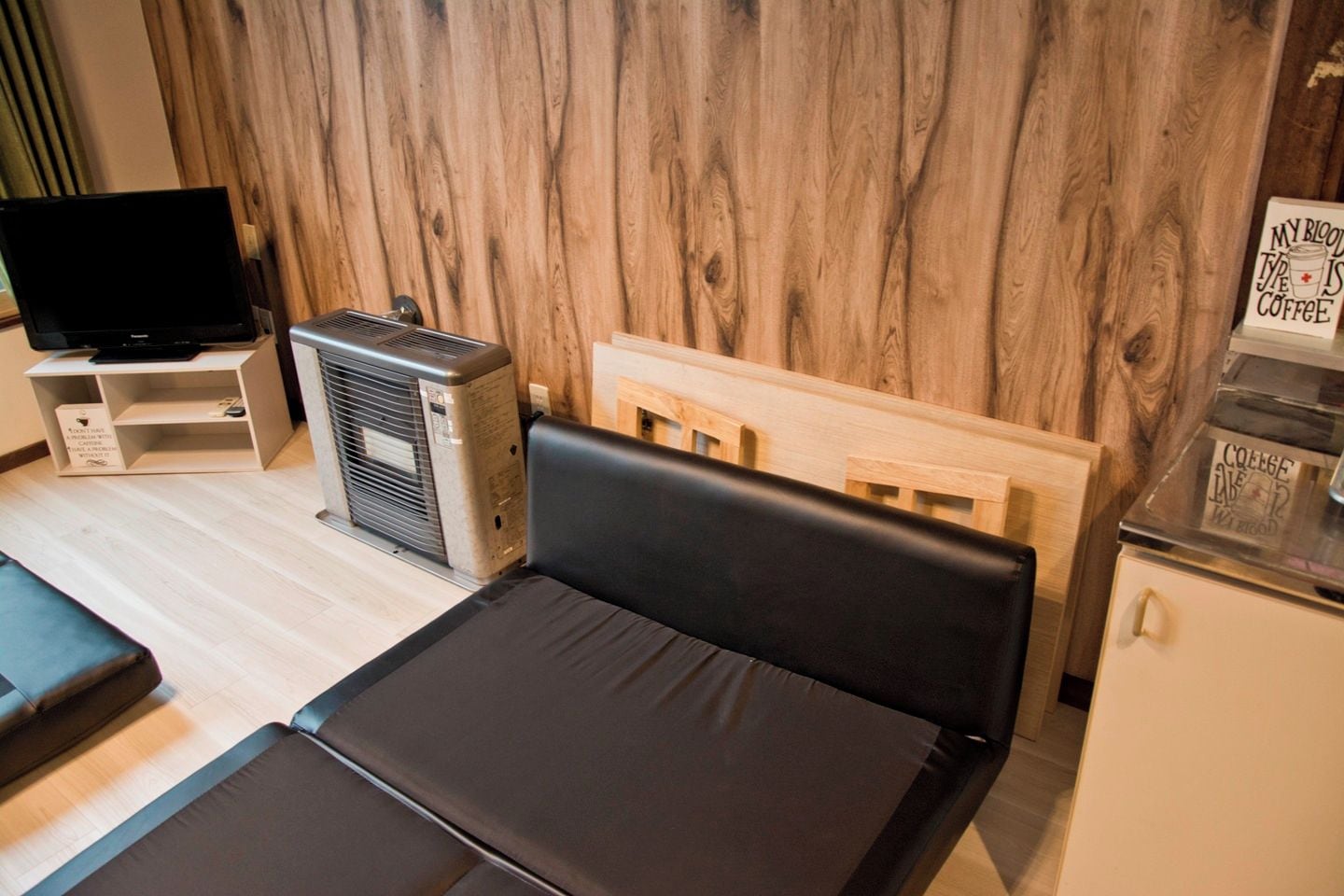 A compact room with a bed, a desk, a television, and an air conditioning unit.