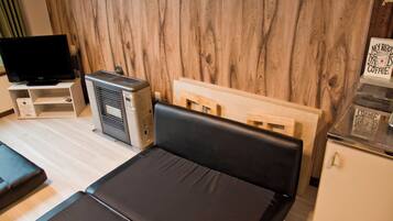 A compact room with a bed, a desk, a television, and an air conditioning unit.