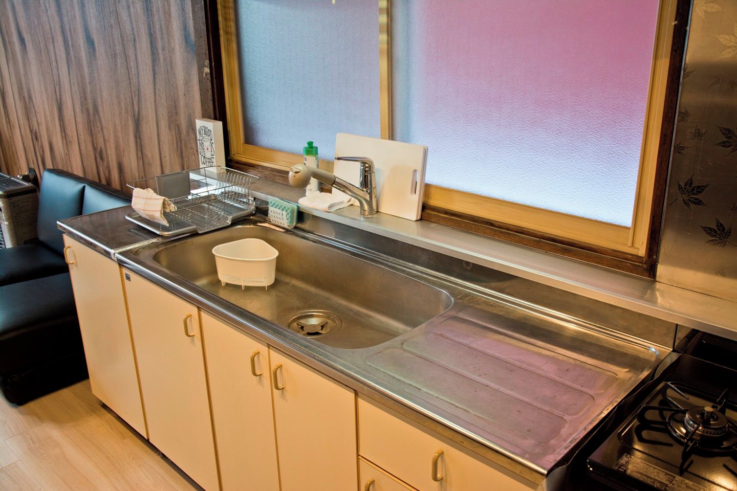 A kitchen with a stainless steel sink, a stove, and a window with a view.