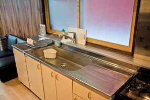 A kitchen with a stainless steel sink, a stove, and a window with a view. - Nagayama tei (Asahikawa)