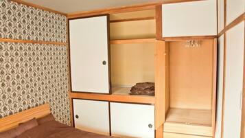 Una habitación con una cama, un armario con varios compartimentos y un papel tapiz estampado.