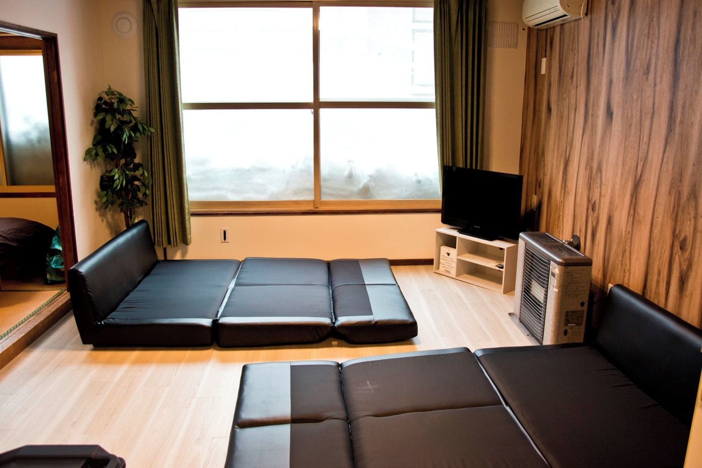 A room with a sofa set, a television, and a wooden wall.