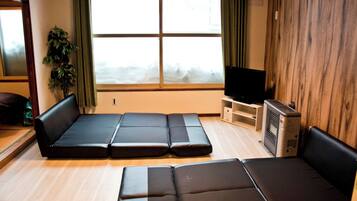 A room with a sofa set, a television, and a wooden wall.