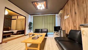 Ein möbliertes Wohnzimmer mit einer Couch, einem Couchtisch, einem Fernseher und einem Computer.