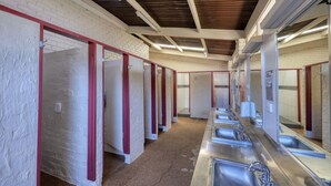 Eine Reihe von Einzelwaschkabinen mit Waschbecken und Spiegeln, getrennt durch rot gestrichene Trennwände.