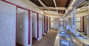 A row of individual stalls with sinks and mirrors, separated by red-painted partitions. - Swan Hill Lifestyle Park (Swan Hill)
