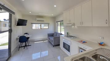 A modern kitchen with white cabinets, a gas stove, and a dining area with a table and chairs.