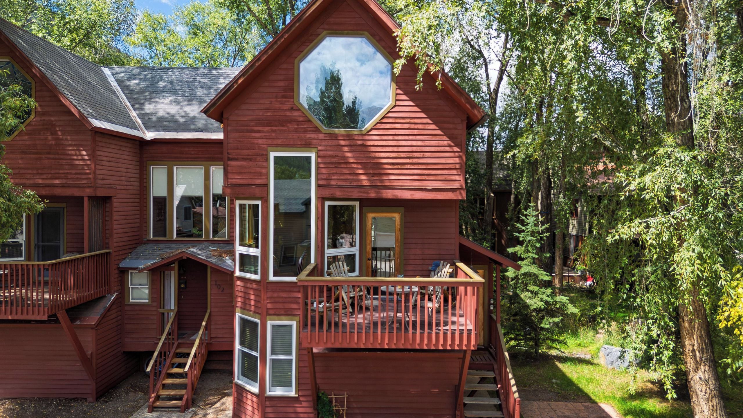 A multi-level wooden cabin with a balcony, stairs, and a large window.
