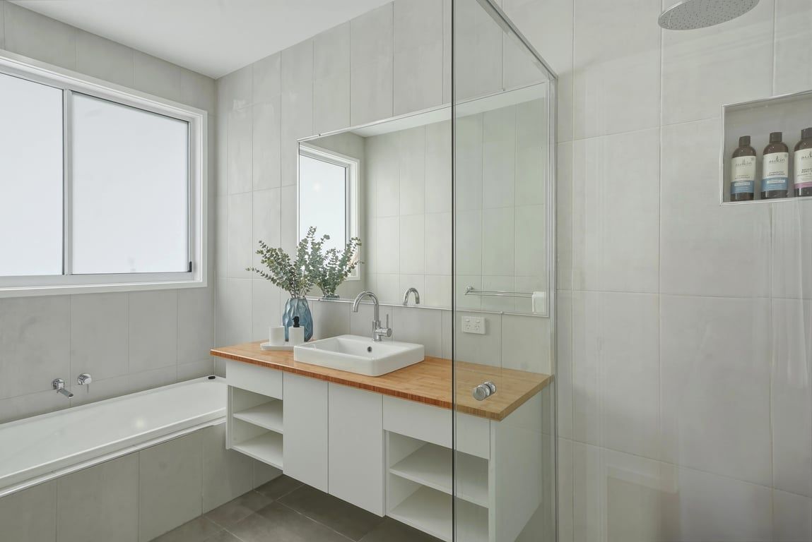 Et moderne badeværelse med badekar, vask, spejl og bruseniche.