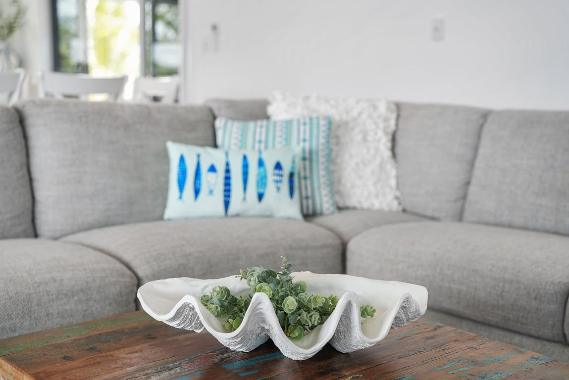 Ein Wohnzimmer mit grauem Sofa, einem Holztisch und dekorativen Kissen.