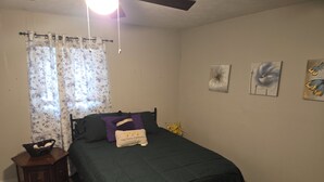 A bedroom with a bed, a nightstand, a window with curtains, and wall art. - Yellow Mellow sleeps 4  (Jackson)