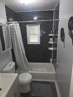 Een badkamer met een bad, toilet en een douchegordijn.