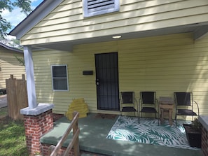 A house with a brick porch, a black door, and a green patterned rug.