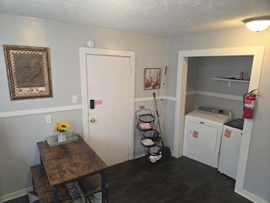 A laundry room with a washing machine, a drying rack, and a fire extinguisher.