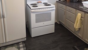 A compact kitchen with a white stove, a refrigerator, and a microwave. There are cabinets and a countertop with various kitchen items. - Yellow Mellow sleeps 4  (Jackson)