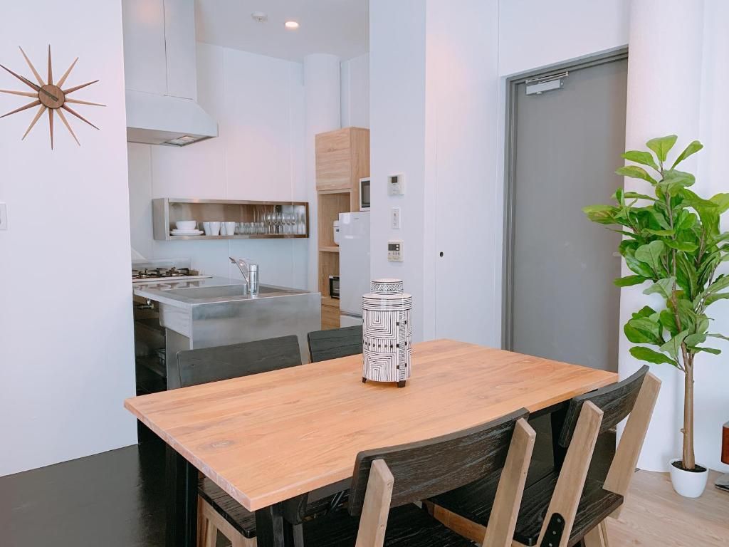 A modern kitchen with white cabinets, a wooden dining table, and a potted plant.