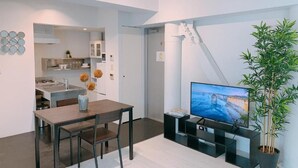 Ein stilvolles Wohnzimmer mit Essbereich, Küche und Fernseher.
