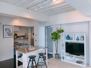 Una cocina moderna con comedor, un mueble de televisión con estantes y una planta en maceta.