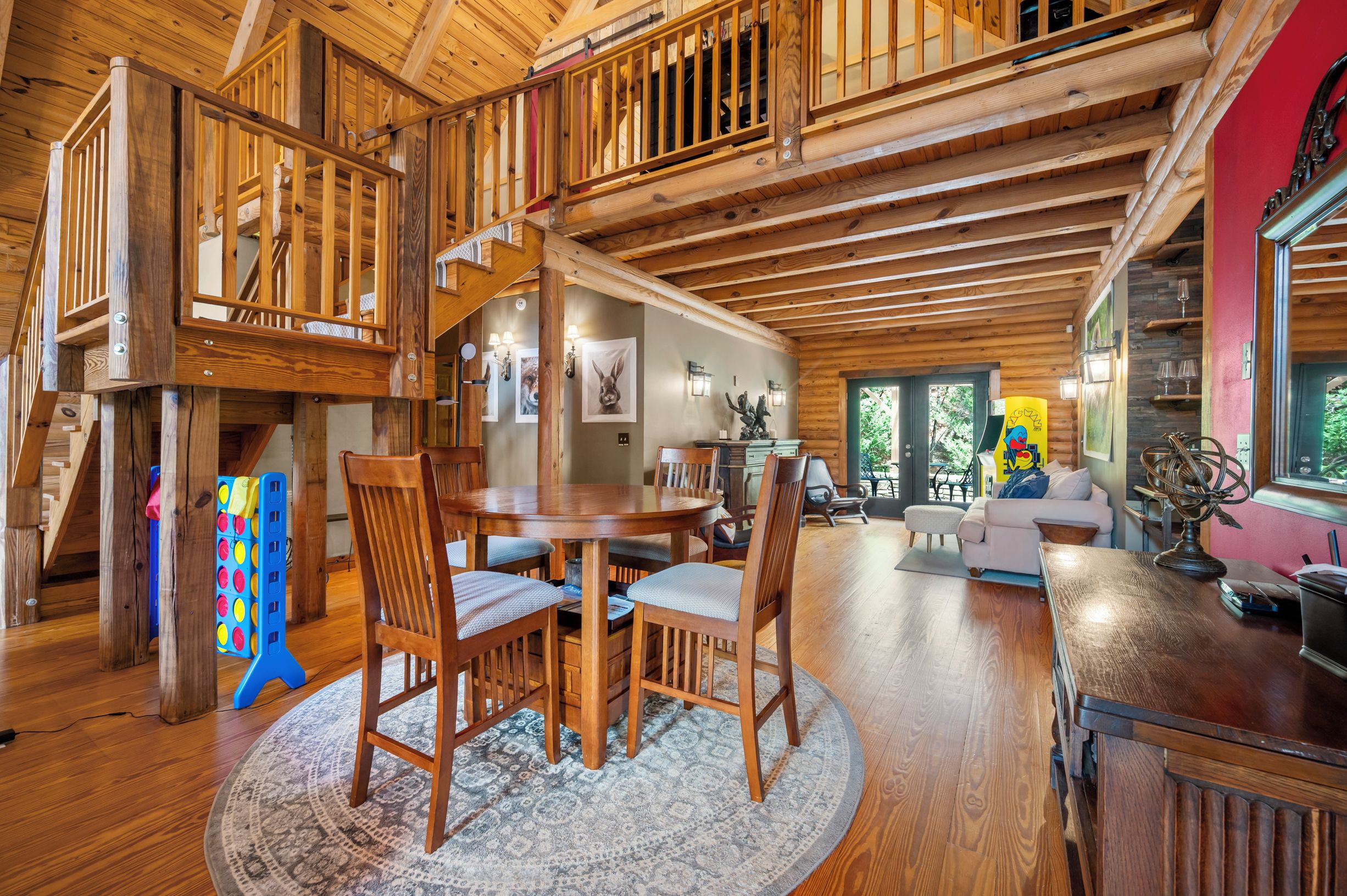 Ein großzügiger Loft-Raum mit hohen Decken, Holzbalken, einem Essbereich mit rundem Tisch und Stühlen sowie einer gemütlichen Sitzecke mit Sofa und Sesseln.
