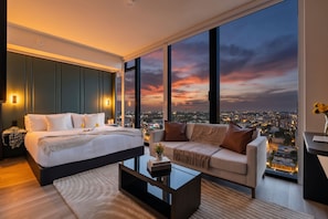 A modern bedroom with a large bed, a sofa, and a city view at dusk. - Designer E11EVEN Studio in Downtown Miami (Miami)