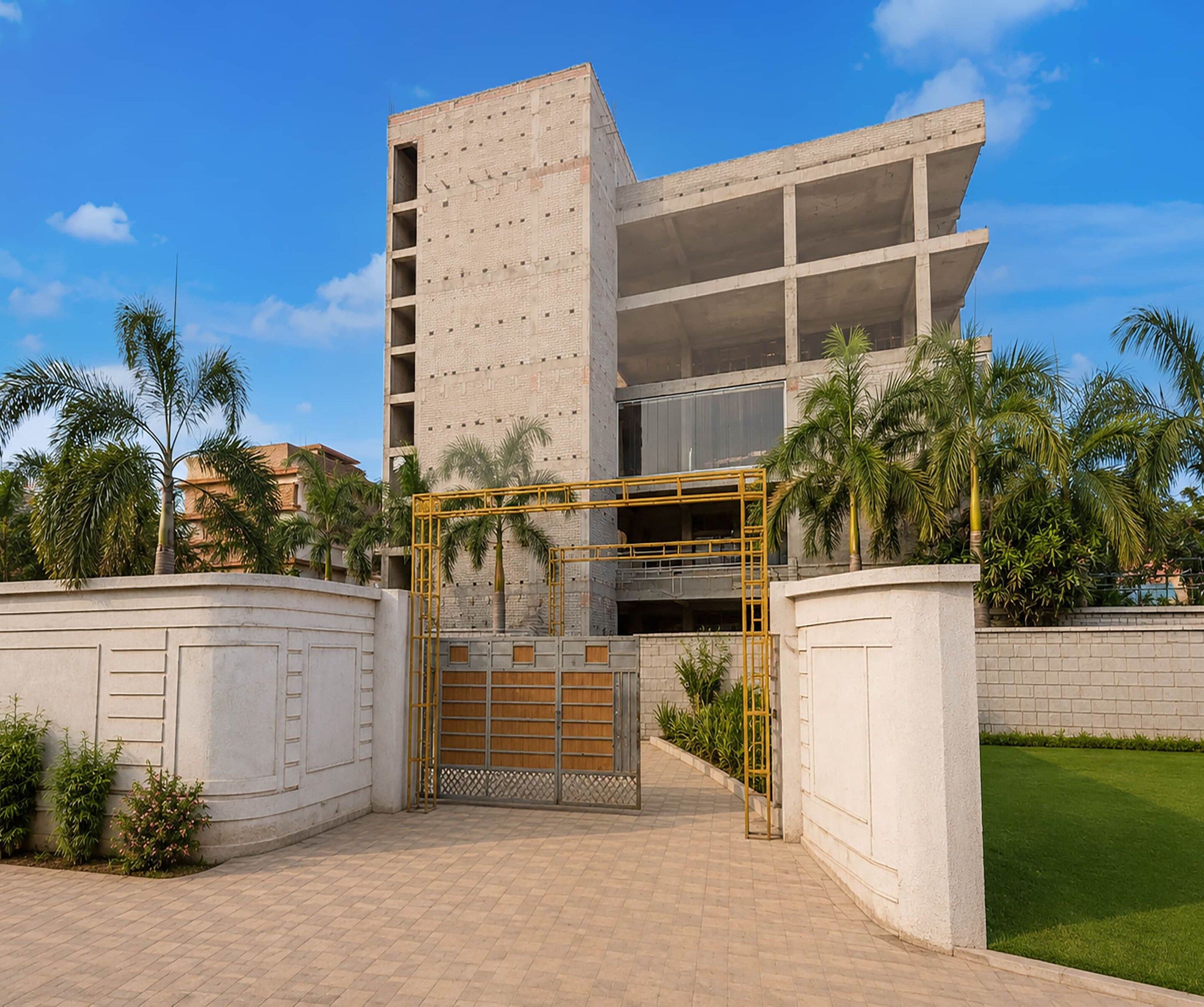 A modern building with a gated entrance, surrounded by palm trees and a well-maintained lawn.