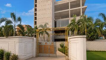 A modern building with a gated entrance, surrounded by palm trees and a well-maintained lawn.