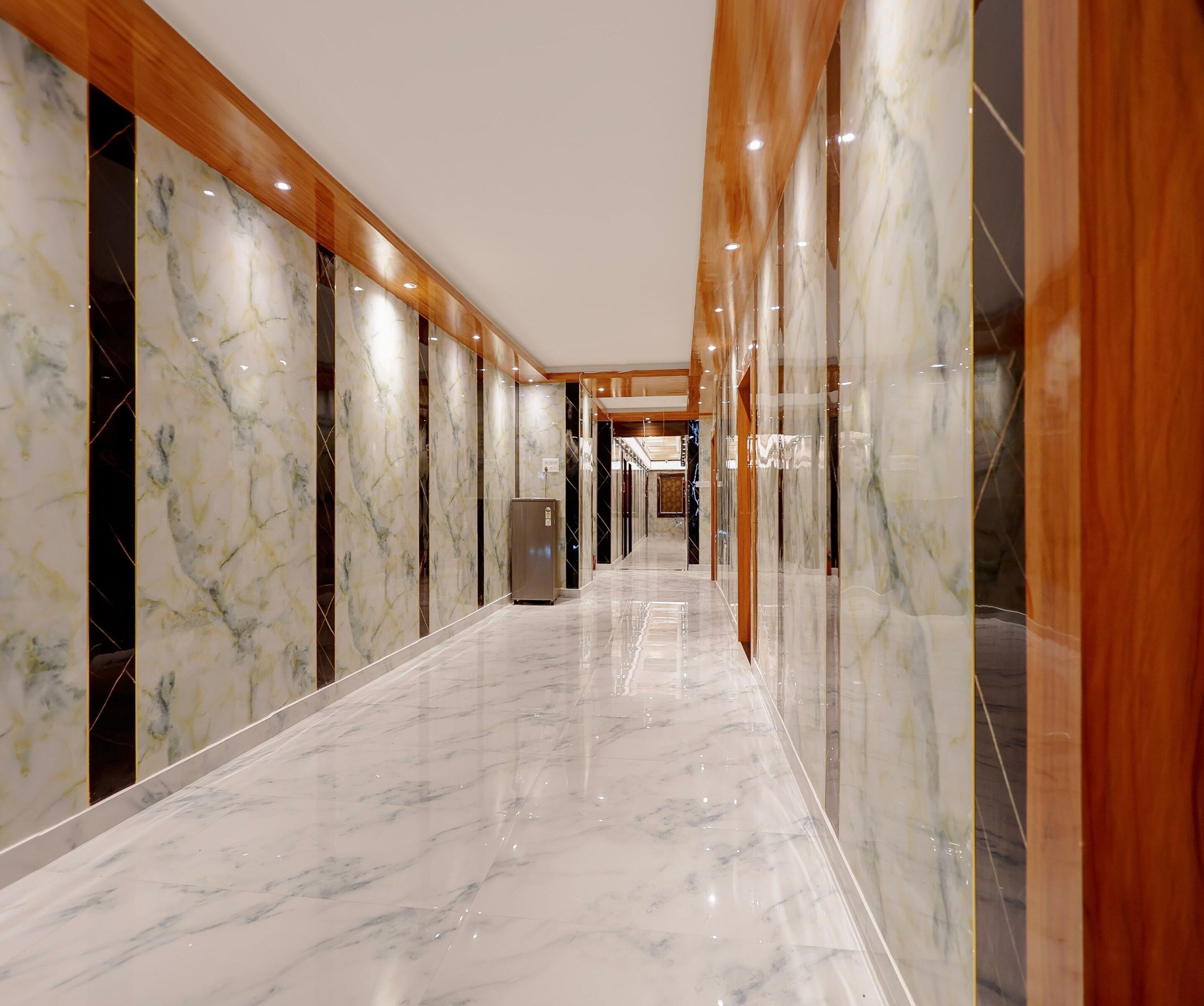 A hallway with marble flooring and wooden paneling, leading to a reception area.