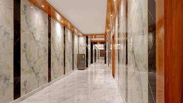 A hallway with marble flooring and wooden paneling, leading to a reception area.