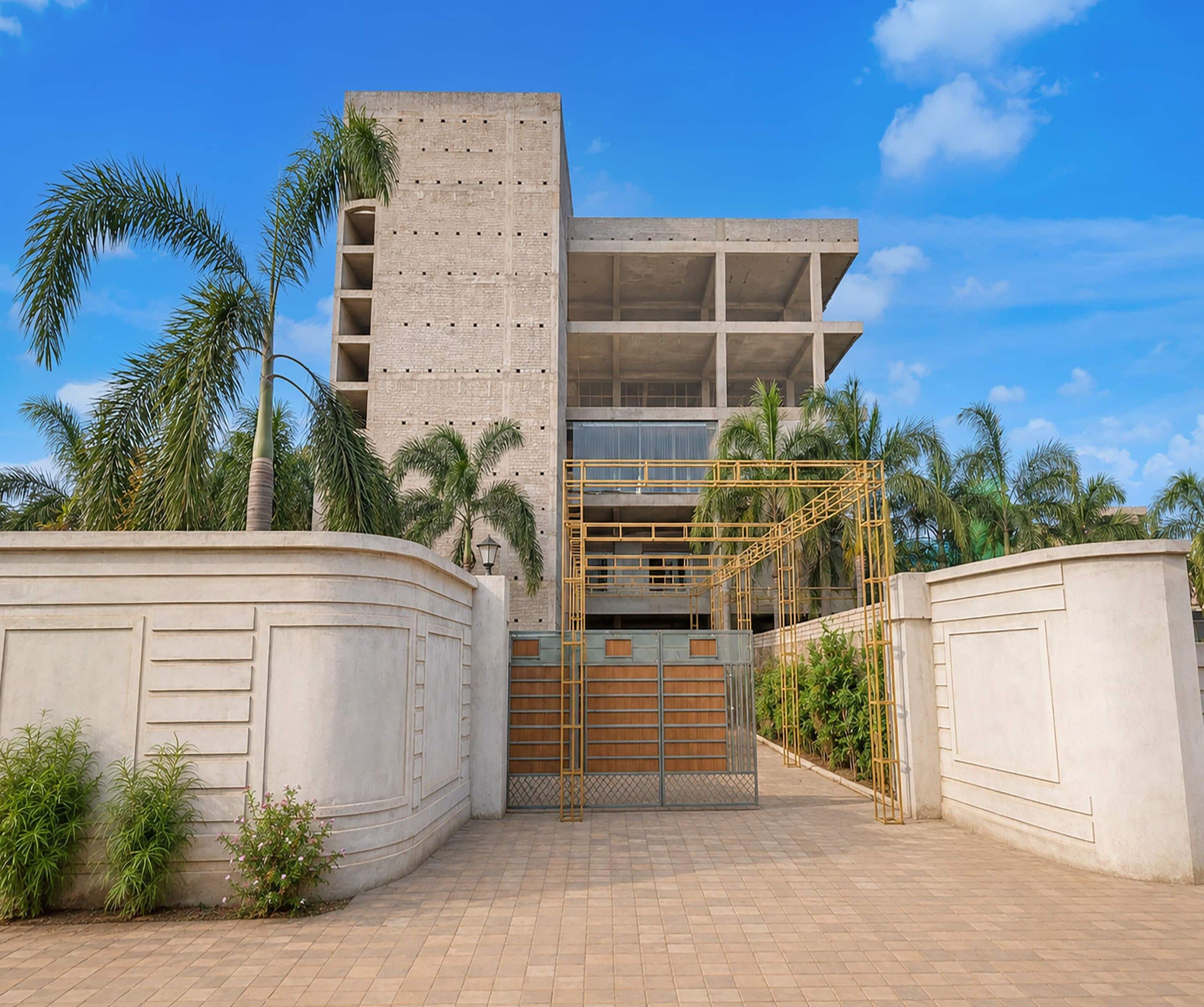 A modern building with a concrete facade, a gated entrance, and a clear sky.