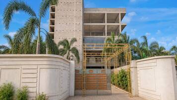 A modern building with a concrete facade, a gated entrance, and a clear sky.