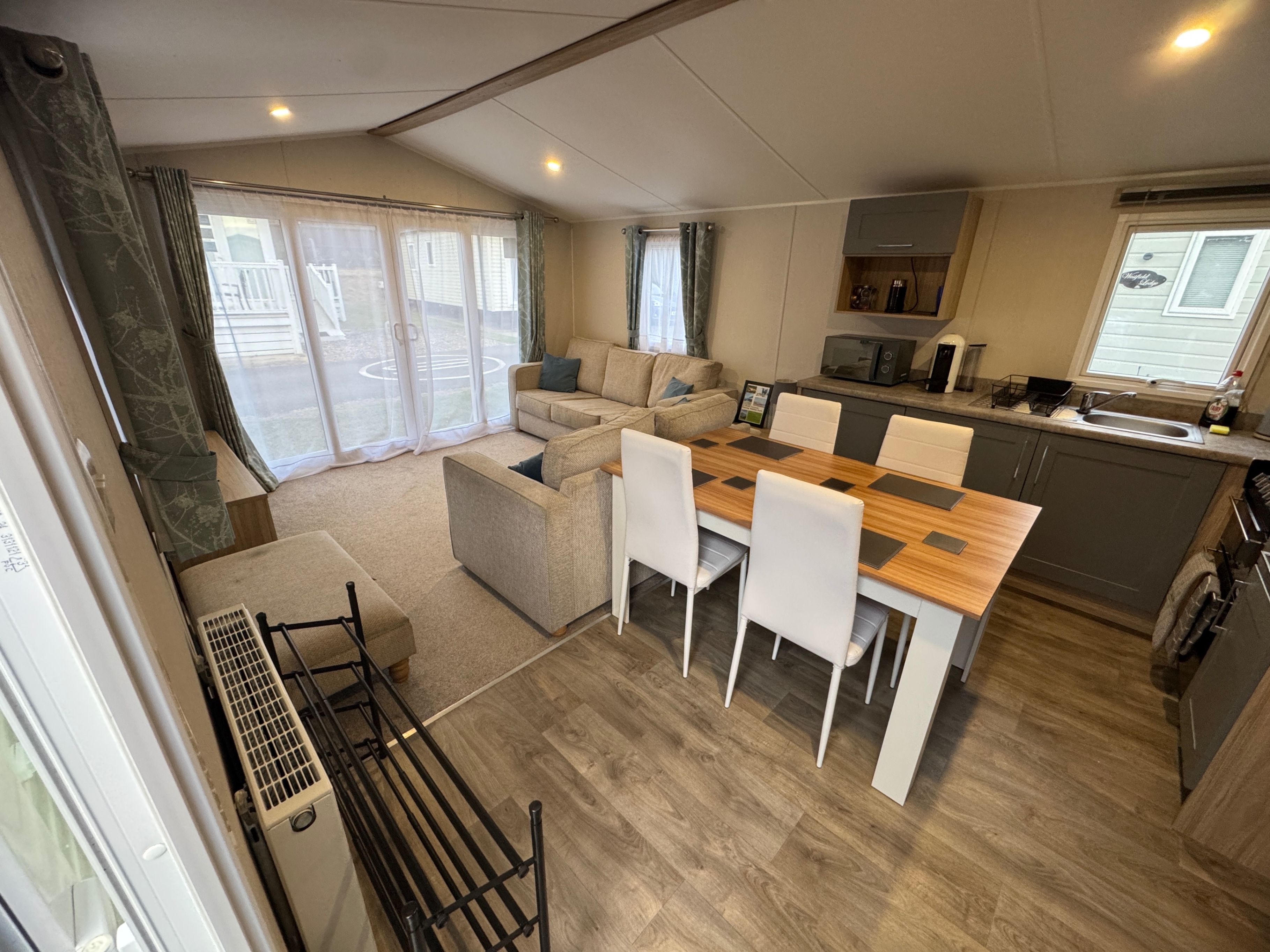 A compact living space with a dining area, kitchenette, and a sliding glass door leading to an outdoor area.