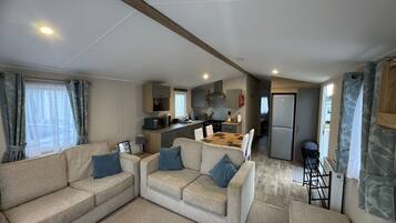 A compact living space with a sofa set, a kitchen area, and a refrigerator.