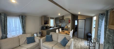 A compact living space with a sofa set, a kitchen area, and a refrigerator.