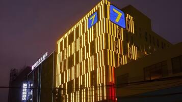A hotel with a modern facade featuring vertical lighting patterns and illuminated signage.