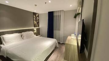 A modern hotel room with a large bed, bedside tables, a flat-screen TV, and a window with curtains.
