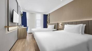 A hotel room with a large bed, a bedside table, a TV, and a window with curtains.