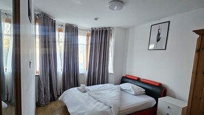 Un dormitorio con cama, mesita de noche, silla y armario.