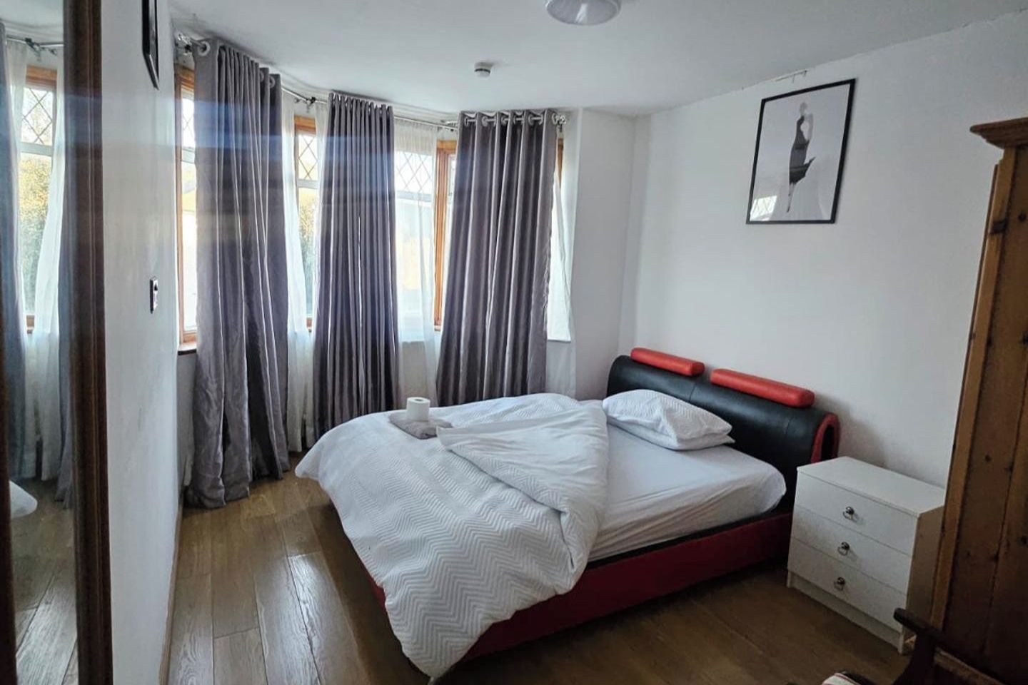 A bedroom with a bed, a nightstand, a dresser, and a framed picture on the wall.