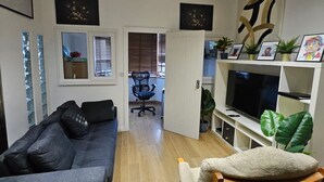 Una sala de estar moderna con un sofá, una butaca, un televisor y una estantería.