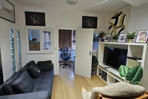 Una sala de estar con un sofá gris, un televisor y una planta.