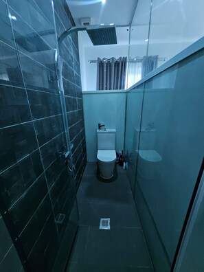 Un baño moderno con cabina de ducha de vidrio, inodoro y lavamanos.
