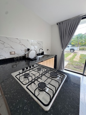 Una cucina moderna con piano cottura a gas, zoccolo in marmo e vista sull'esterno.