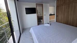 Un dormitorio con cama, televisor y vistas al exterior.