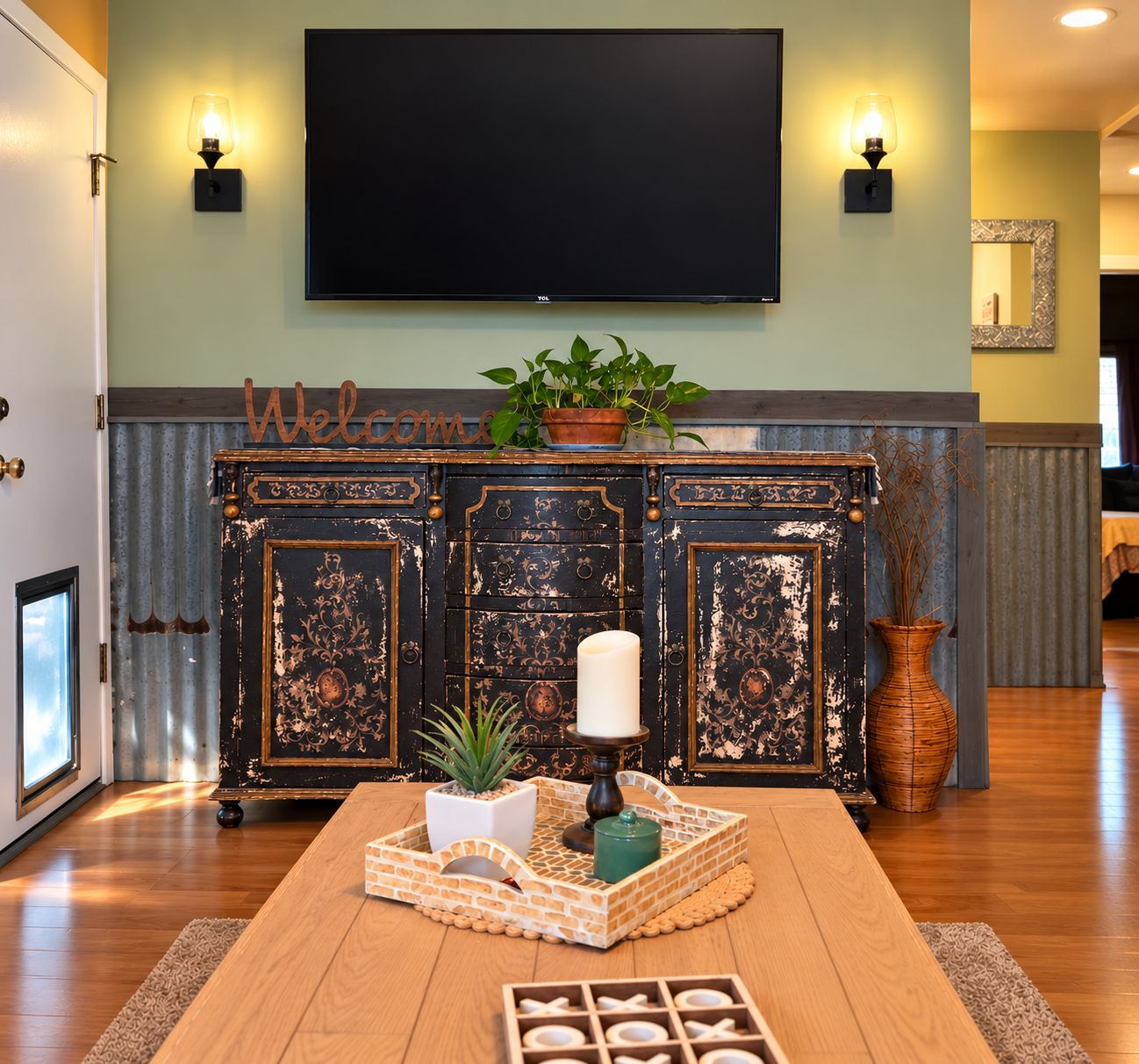 A living room with a wooden coffee table, a potted plant, a candle, and a wall-mounted flat-screen TV.