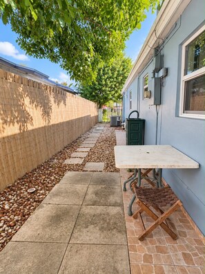 A patio area with a table and chairs, a bamboo fence, and a pathway with stepping stones.
