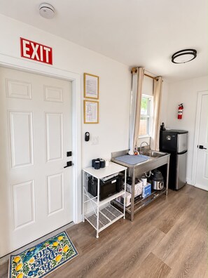 A compact kitchenette with a sink, a microwave, a refrigerator, and a small countertop.