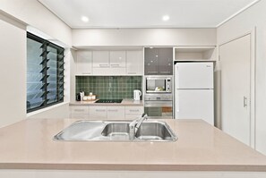 A modern kitchen with a double sink, stainless steel appliances, and a green tiled backsplash.