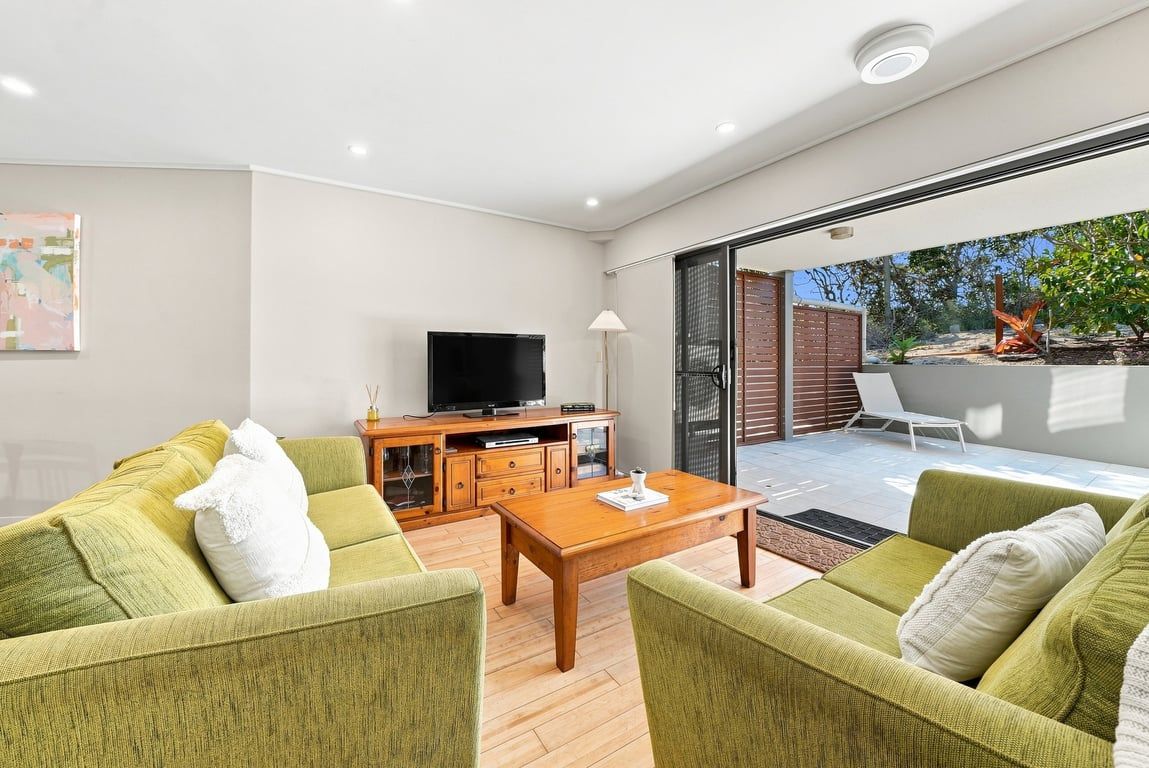 A modern living room with a sofa set, a coffee table, and a flat-screen TV.