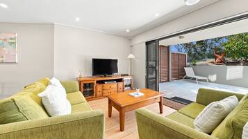 A modern living room with a sofa set, a coffee table, and a flat-screen TV.