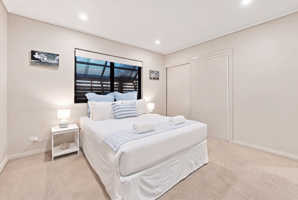A bedroom with a large bed, bedside tables, a wardrobe, and artwork on the walls.